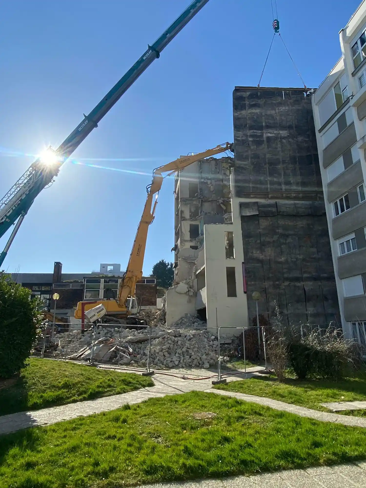 Démolition d'un bâtiment à Amiens avec une grue jaune et un chantier en cours sous un ciel bleu.